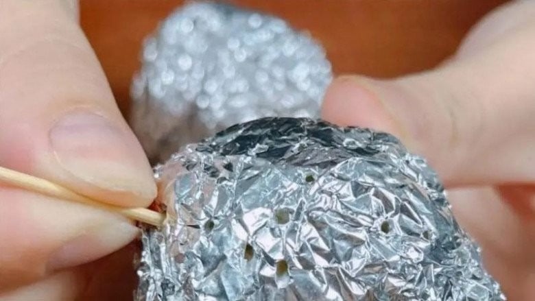 Dùng tăm chọc vài lỗ nhỏ trên quả bóng giấy bạc.