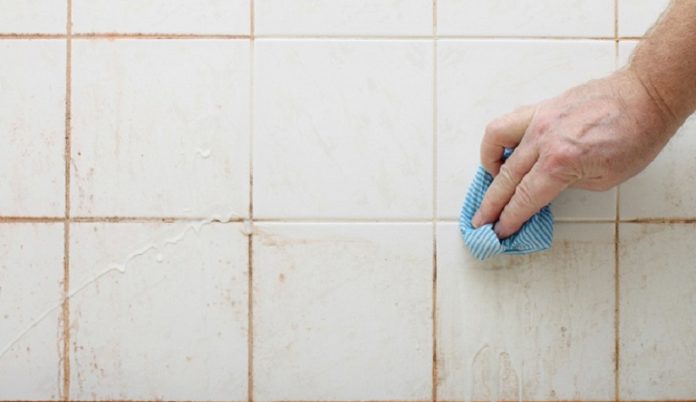 cleaning dirty shower and bathroom tiles with mould with blue cloth